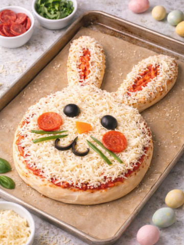 Healthy Sourdough Easter Bunny Pizza on a baking sheet at an angle, topped with mozzarella, olives, pepperoni, and bell peppers for a festive Easter dinner idea.