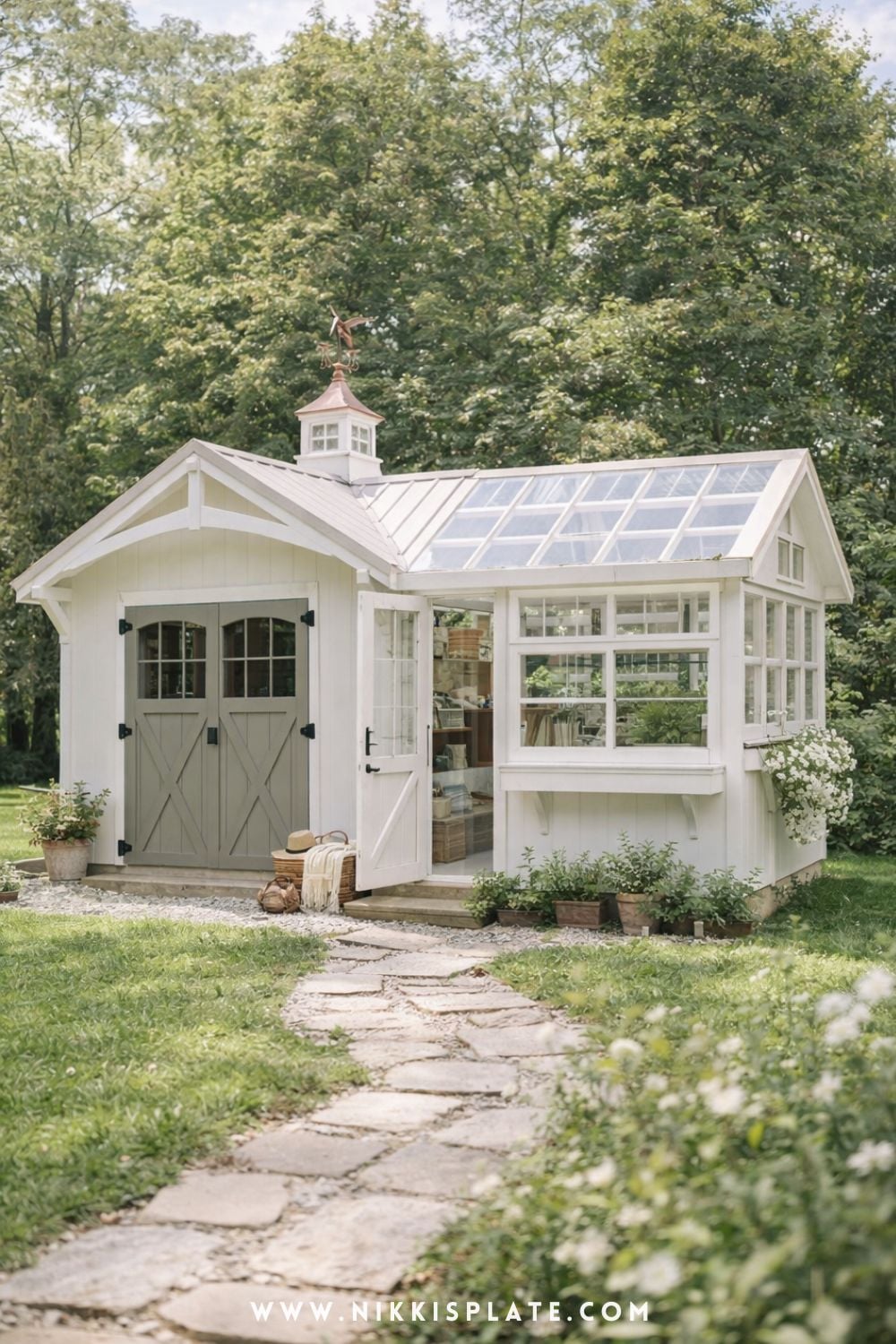 backyard shed greenhouse conversion with white wood siding and glass windows in a garden setting