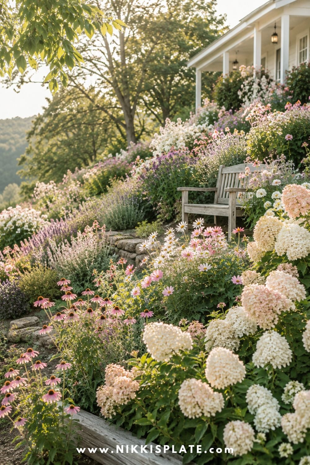Sloped backyard landscaping with hillside flower beds, soft cottage flowers, layered perennials, and a cozy farmhouse garden bench.