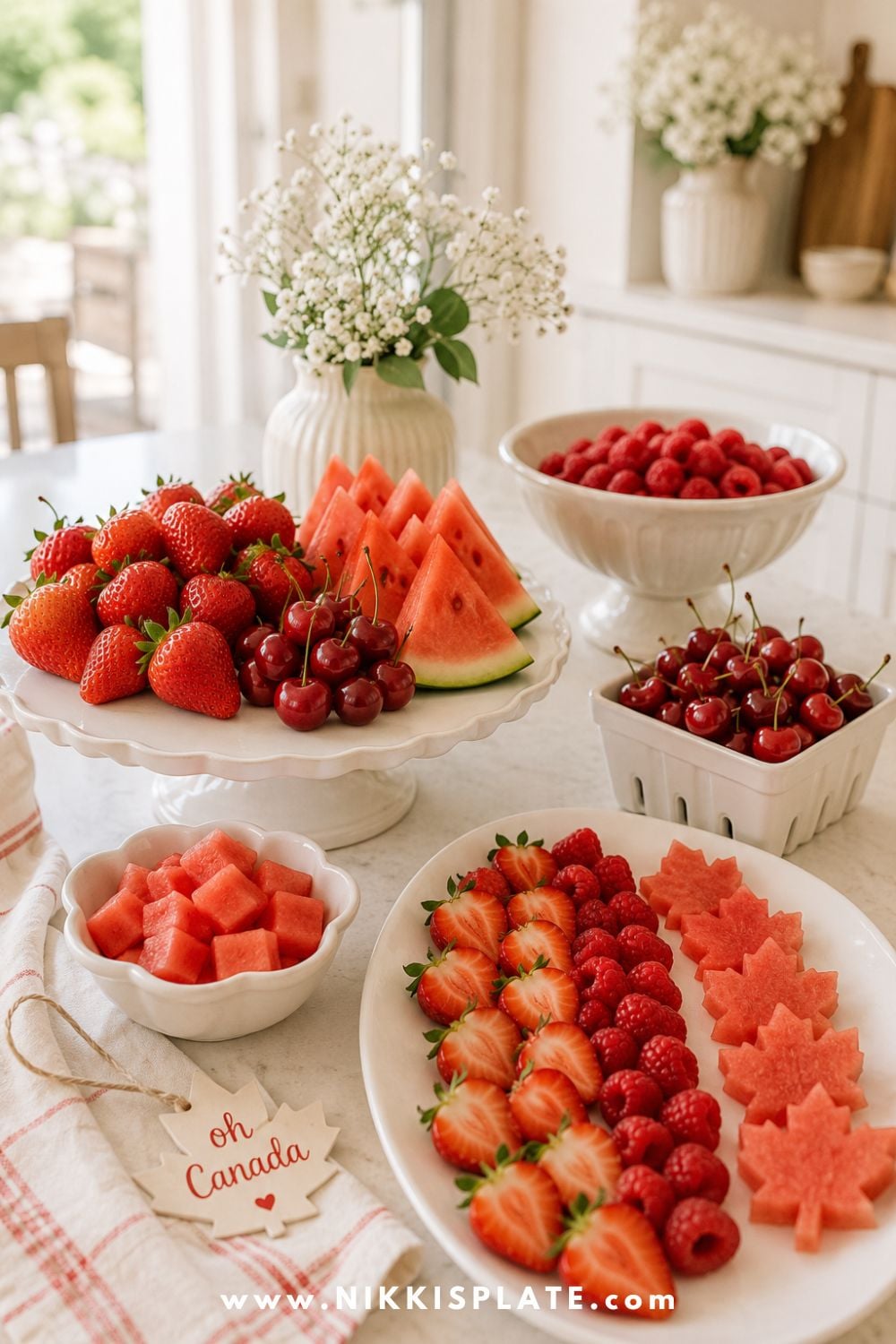 Canada Day fruit platter with strawberries, raspberries, cherries, watermelon slices, and maple leaf watermelon cutouts styled on a bright kitchen counter.