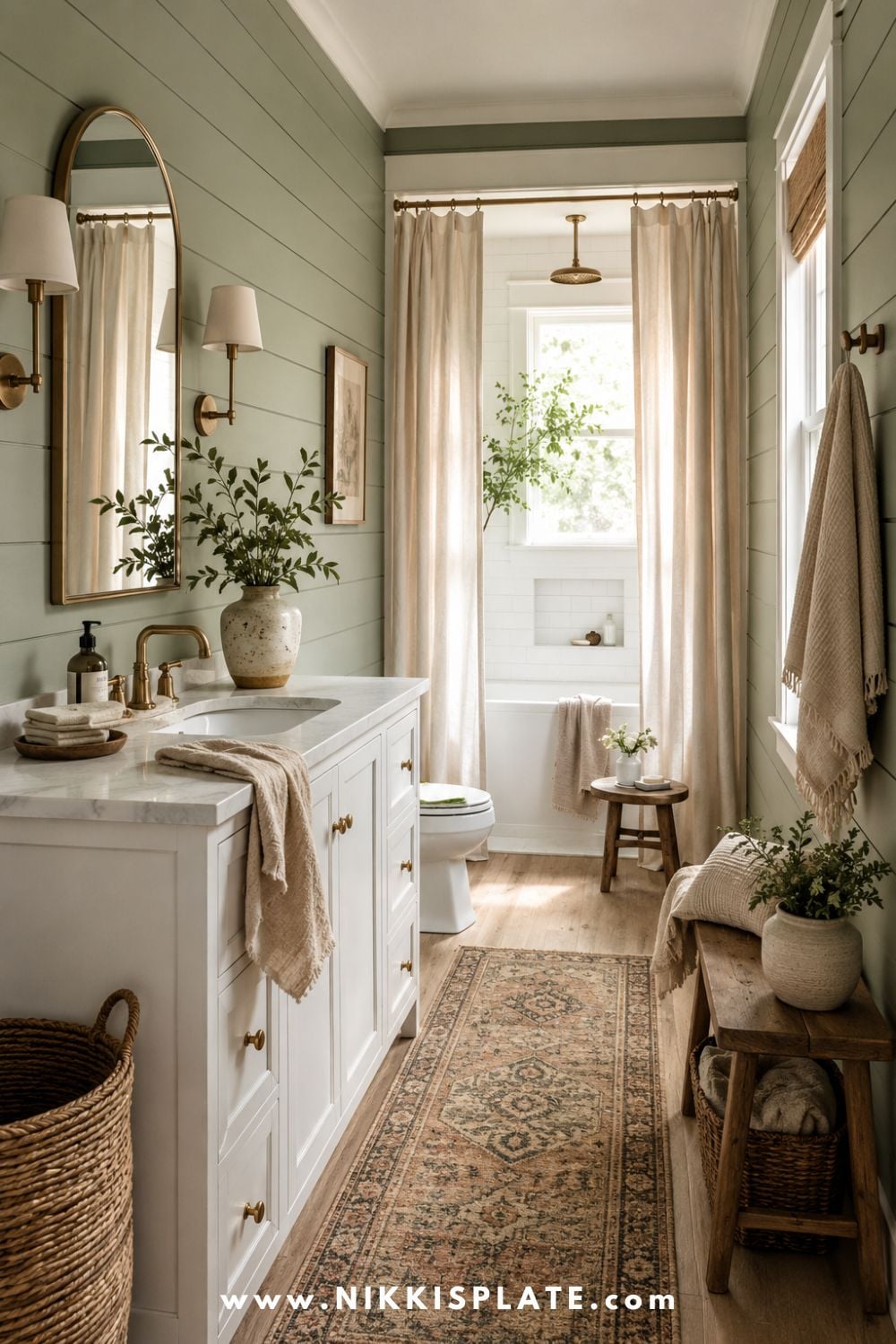 Narrow modern farmhouse bathroom with green shiplap walls, white vanity, brass mirror, vintage runner rug, linen curtains, wood bench, woven baskets, and soft natural light.