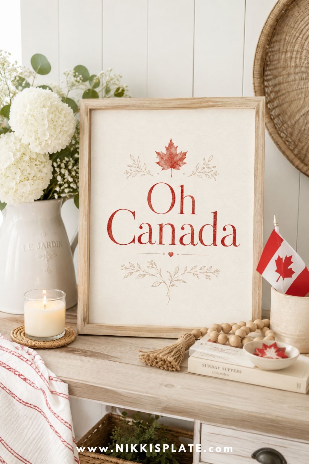 ed Oh Canada printable styled on a neutral mantel with white hydrangeas, a mini Canadian flag, candle, wood beads, and soft Canada Day decor.