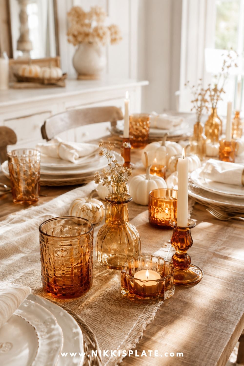 Amber glass candleholders, drinking glasses and bud vases adding warmth to neutral fall dining table decor.