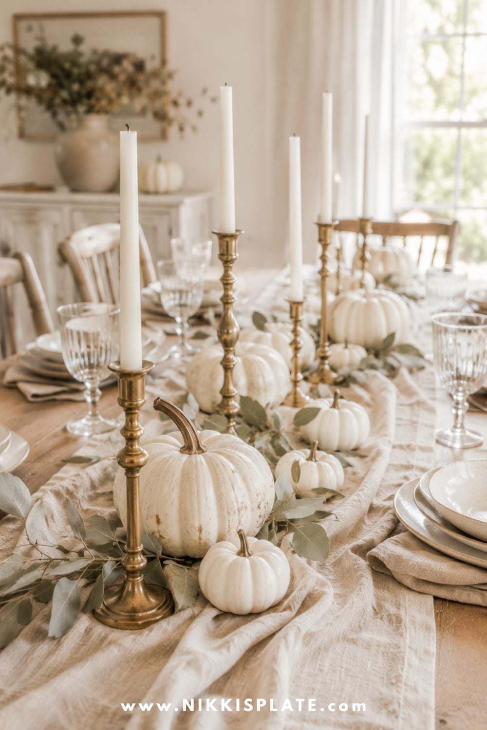 Aged brass candlesticks and creamy white pumpkins arranged over a relaxed linen runner for elegant fall table decor.