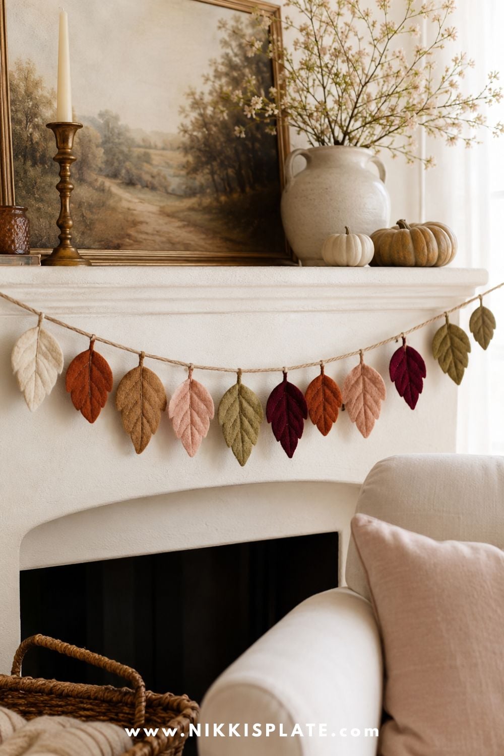 Handmade felt leaf garland in cream, rust, caramel, blush and olive draped across a cozy farmhouse fireplace mantel.