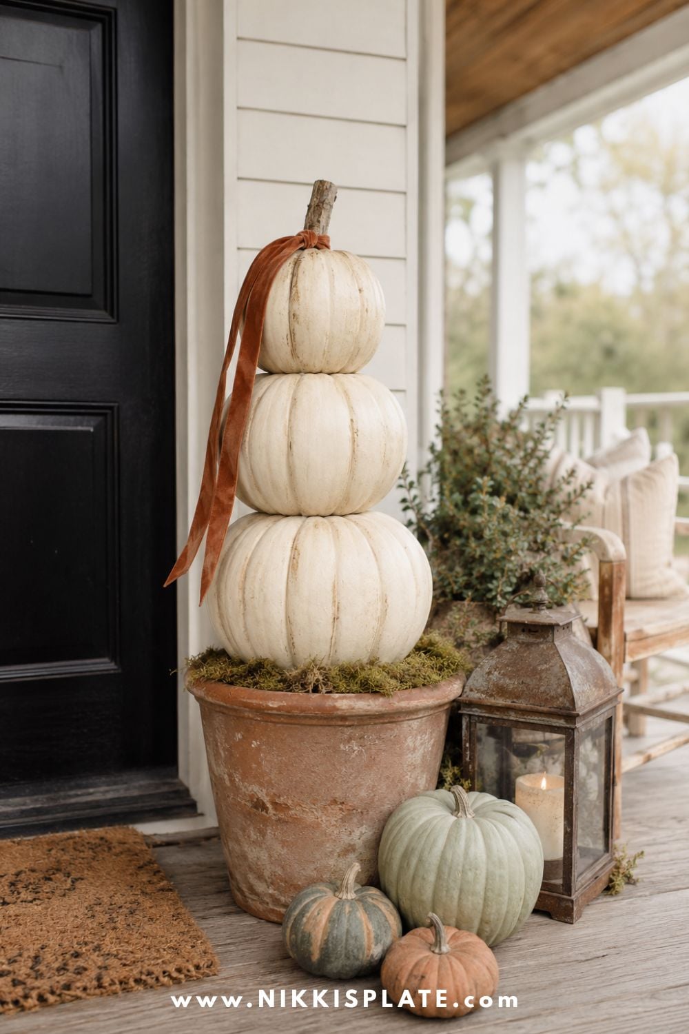 Three stacked cream faux pumpkins in an aged terracotta planter creating an elegant DIY fall porch topiary.