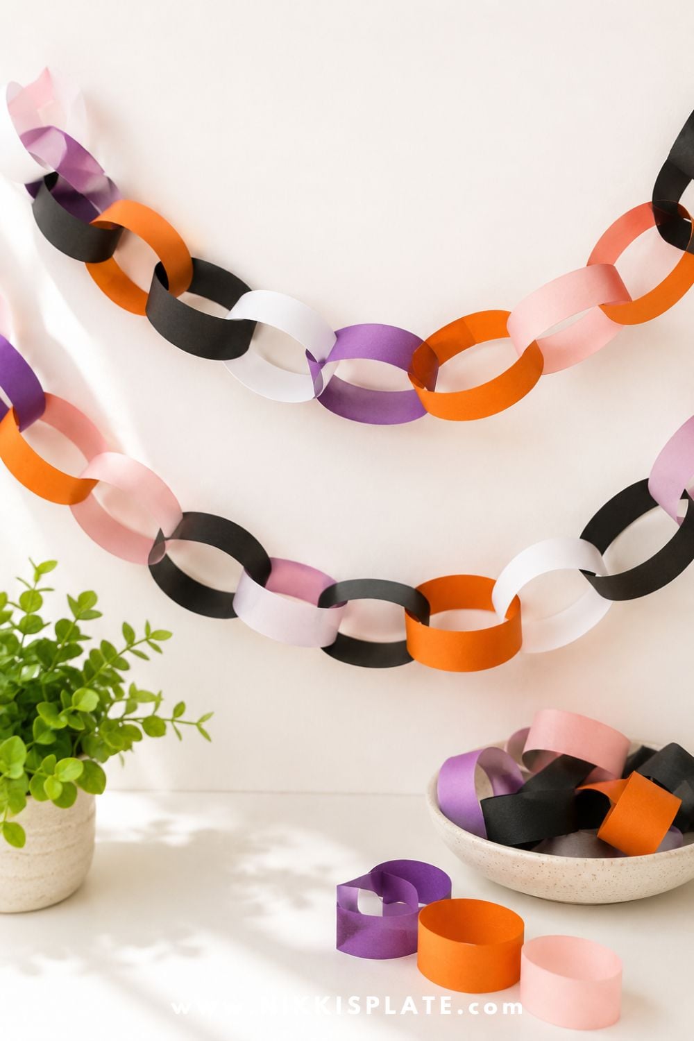 Orange, black, white, purple, and blush paper chain Halloween garland displayed on a clean background for an easy Halloween decoration craft for kids.