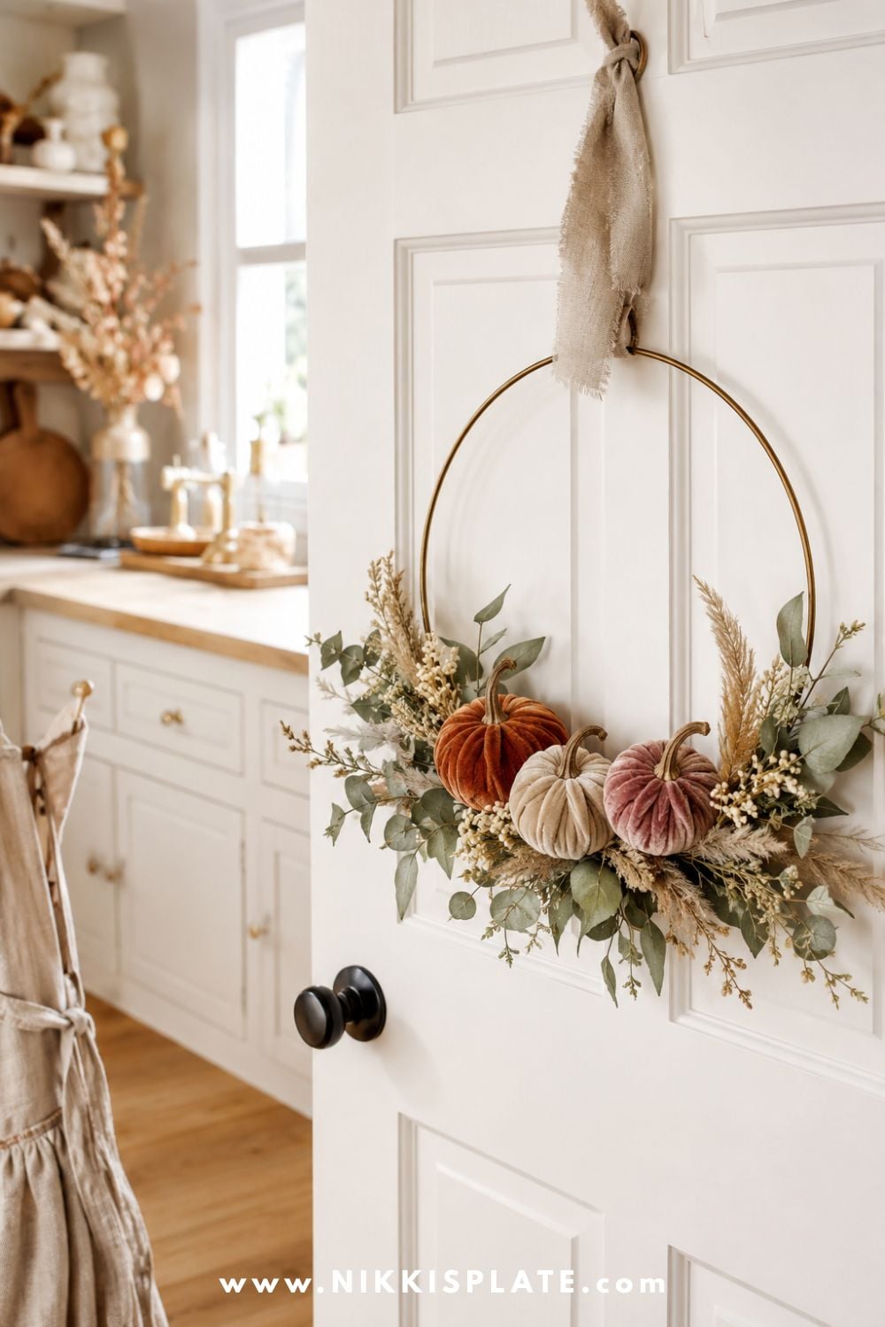 Brass hoop wreath decorated with miniature velvet pumpkins, eucalyptus, cream berries and dried grasses for simple fall door decor.