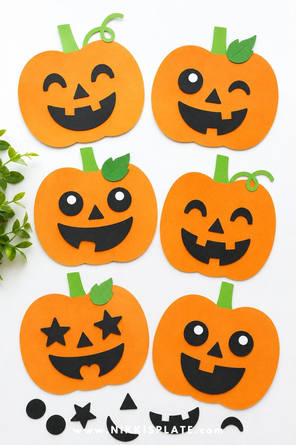 Orange paper pumpkin cutouts with funny jack-o-lantern faces made from black paper shapes for an easy Halloween craft for kids.