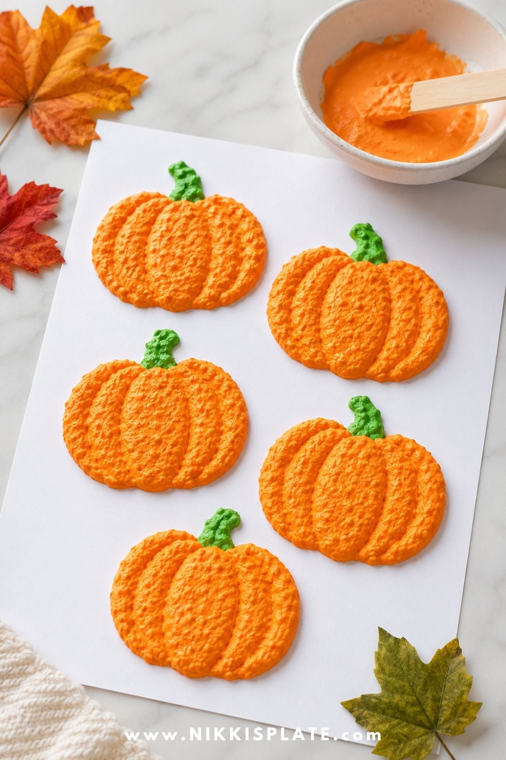 Orange puffy paint pumpkin crafts with green stems on white paper for a fun textured Halloween craft activity for toddlers and kids.