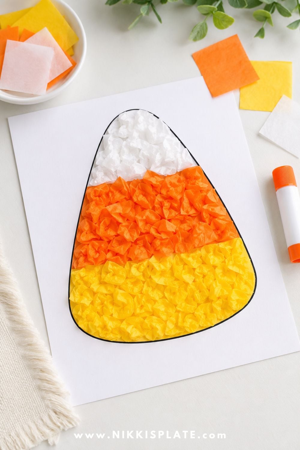 Tissue paper candy corn craft with crinkled yellow, orange, and white tissue pieces for an easy Halloween craft for toddlers and preschoolers.