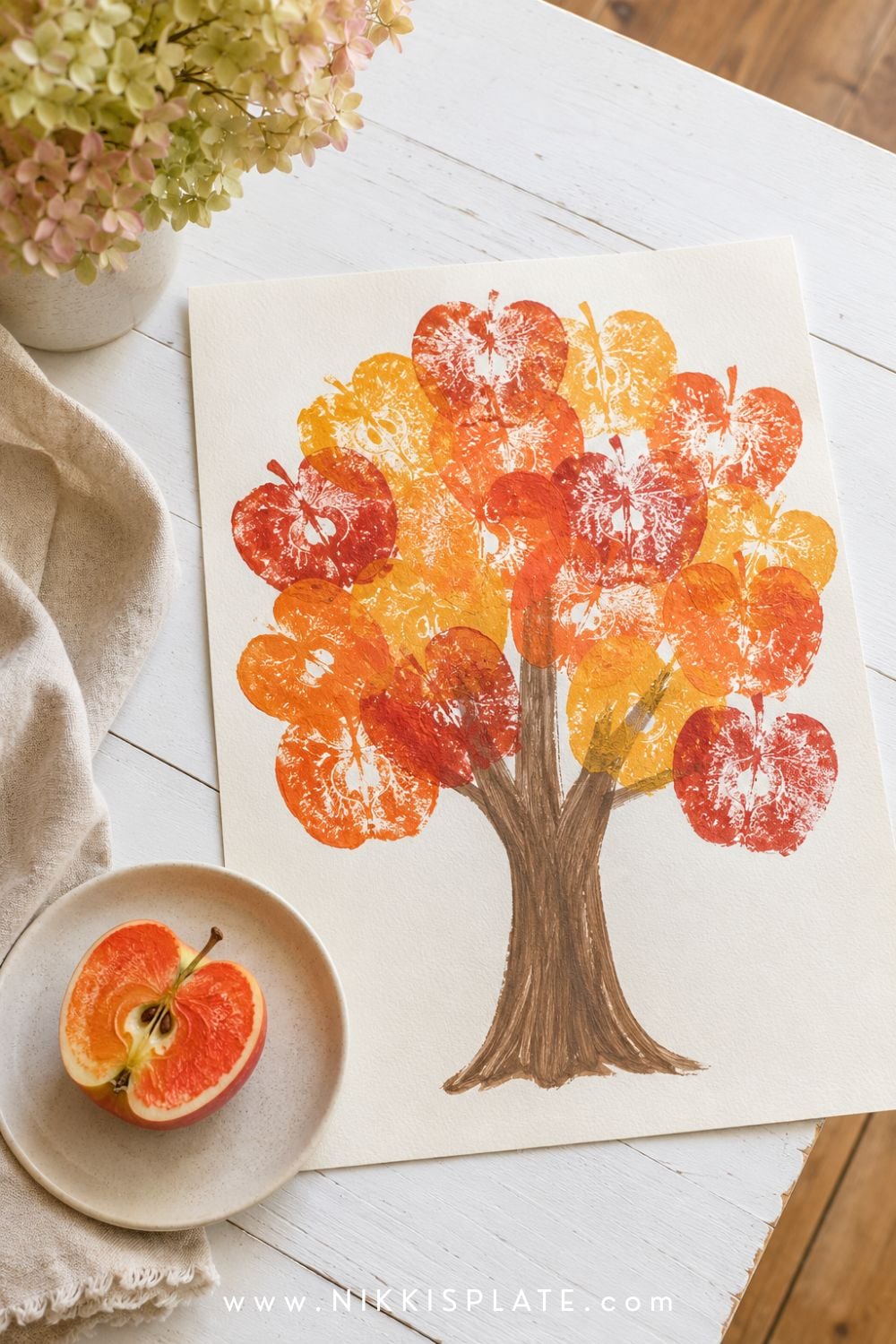 Apple stamp fall tree craft for kids with colorful apple prints forming a full autumn canopy on white paper.