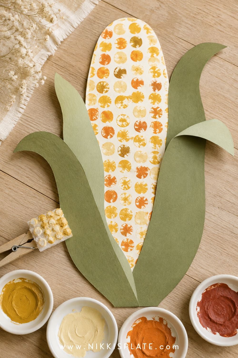 Bubble wrap corn craft for kids with dotted yellow, cream and orange kernels surrounded by green paper husks.