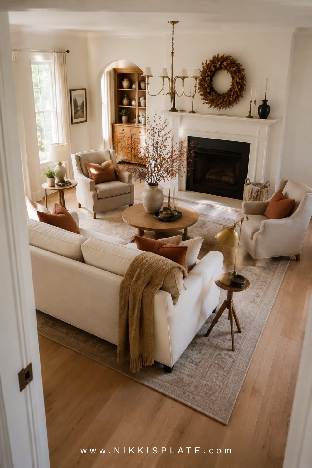 Cream sofa and two linen chairs rearranged around a round oak table for a cozy fall conversation area.
