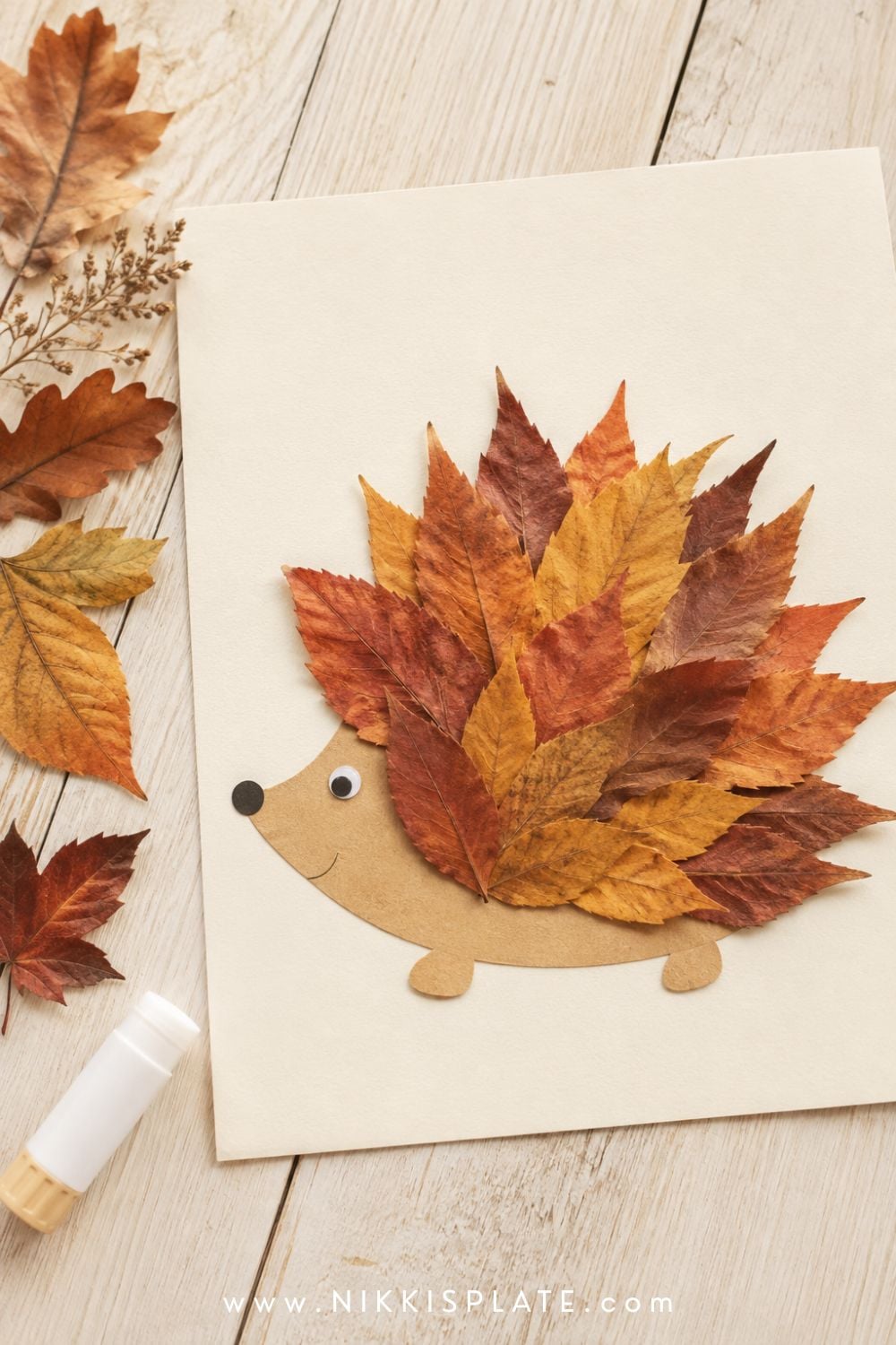 Fall leaf hedgehog craft with real red, orange and golden leaves arranged as colorful pointed quills.