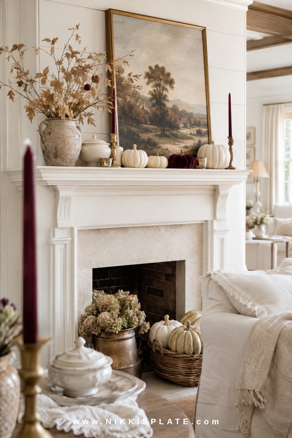 Neutral farmhouse fall mantel accented with deep burgundy candles, a plum velvet pumpkin, muted foliage and vintage artwork.