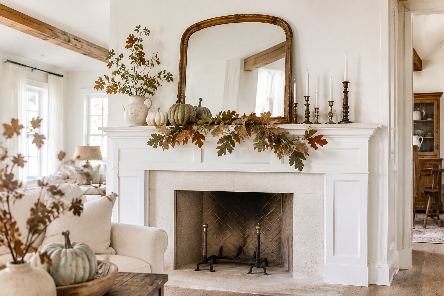 Fall mantel decor ideas featuring neutral pumpkins, autumn garland, vintage mirror and brass candlesticks on a farmhouse fireplace.