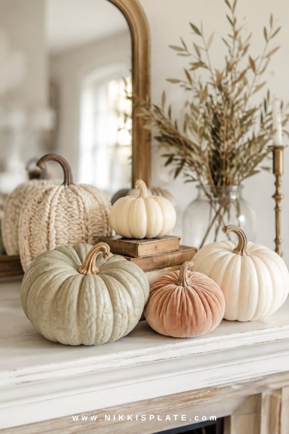 Neutral pumpkin fall mantel decor arranged in odd-numbered groupings with warm wood, pottery and soft autumn branches.