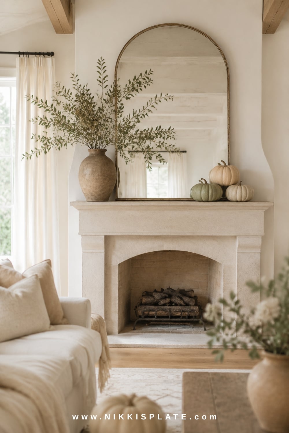Simple neutral fall mantel decor with a pale pumpkin, cream vase, wood candlestick and softly framed landscape art.