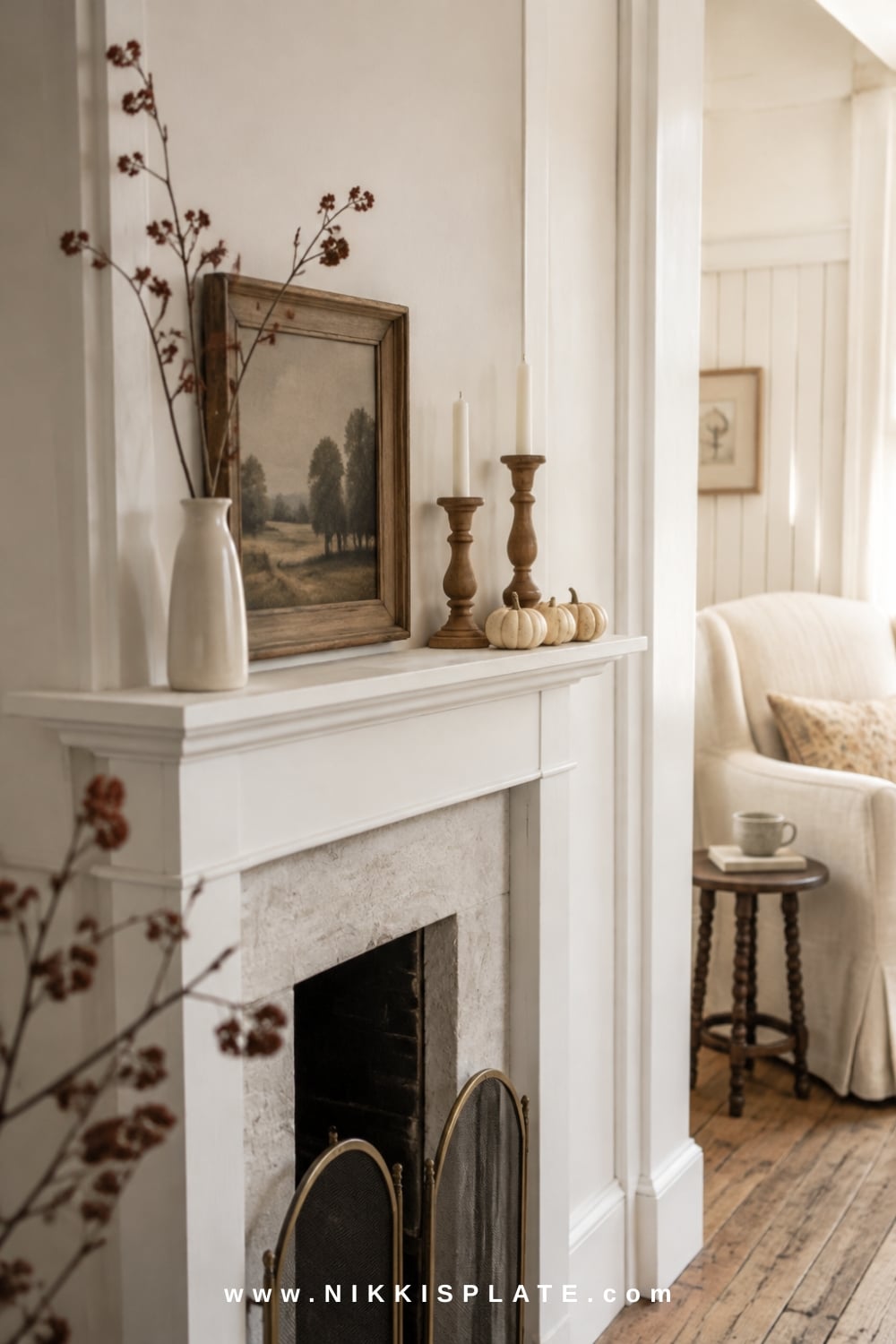 Small fall mantel styled with a large landscape print, slim cream vase, muted branches, wood candlesticks and mini pumpkins.