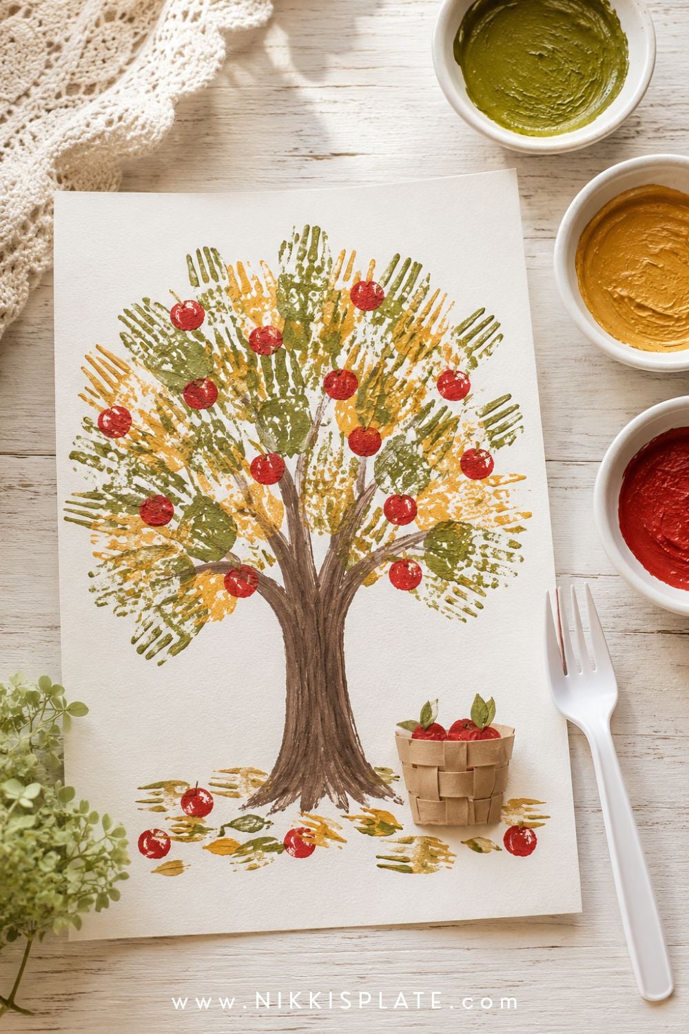 Fork-painted apple tree craft with textured green and golden leaves, small red apples and a brown trunk.