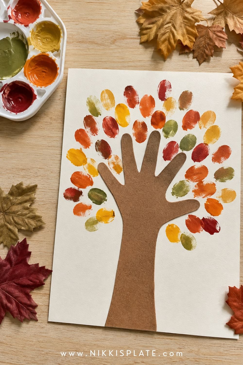 Handprint fall tree craft for kids with a brown paper handprint trunk and colorful fingerprint autumn leaves.