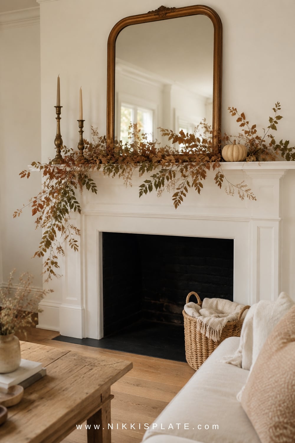 Airy rust and olive fall garland draped asymmetrically across a warm white farmhouse fireplace mantel.