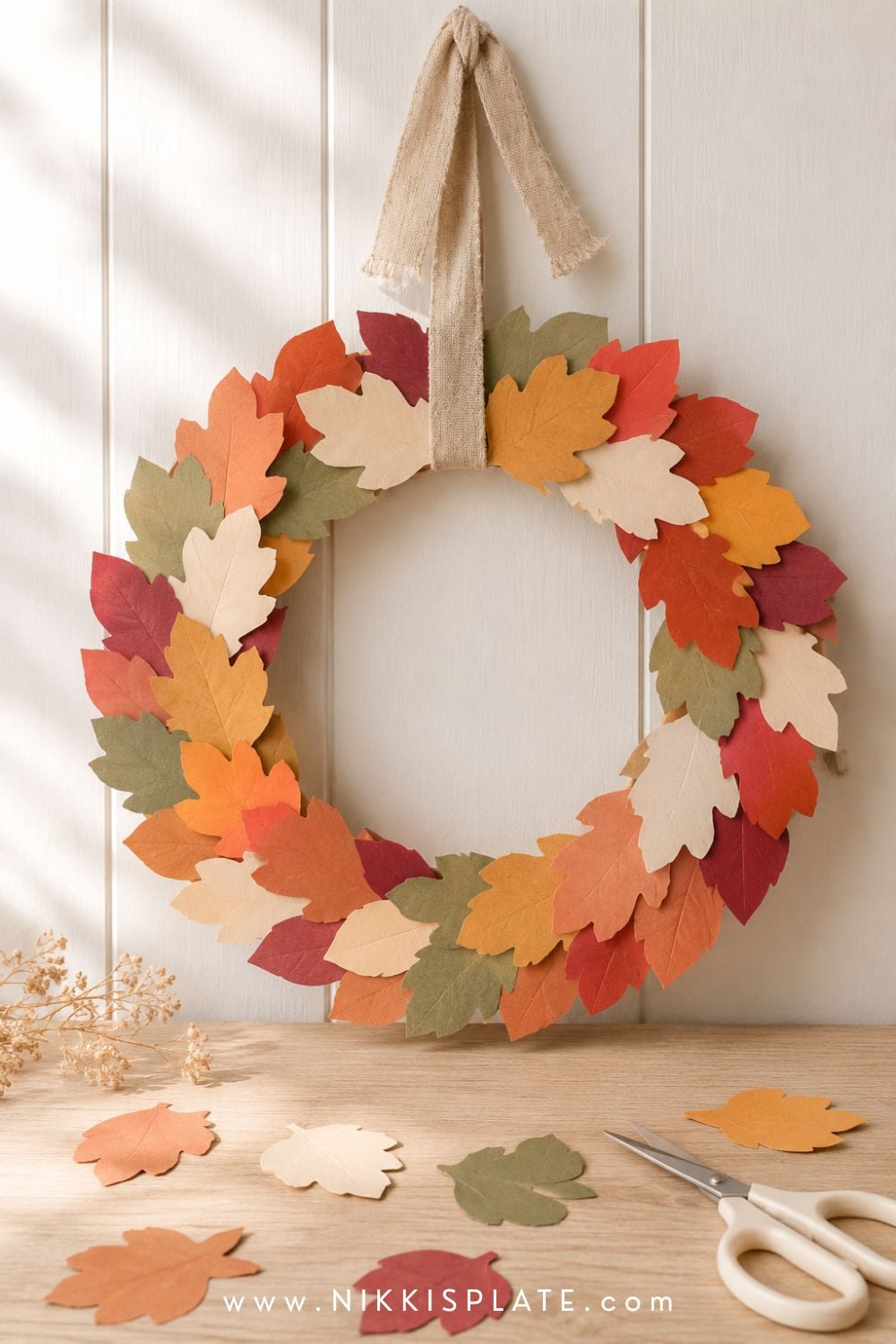 Paper leaf wreath fall craft made with overlapping rust, mustard, cranberry and olive construction paper leaves.
