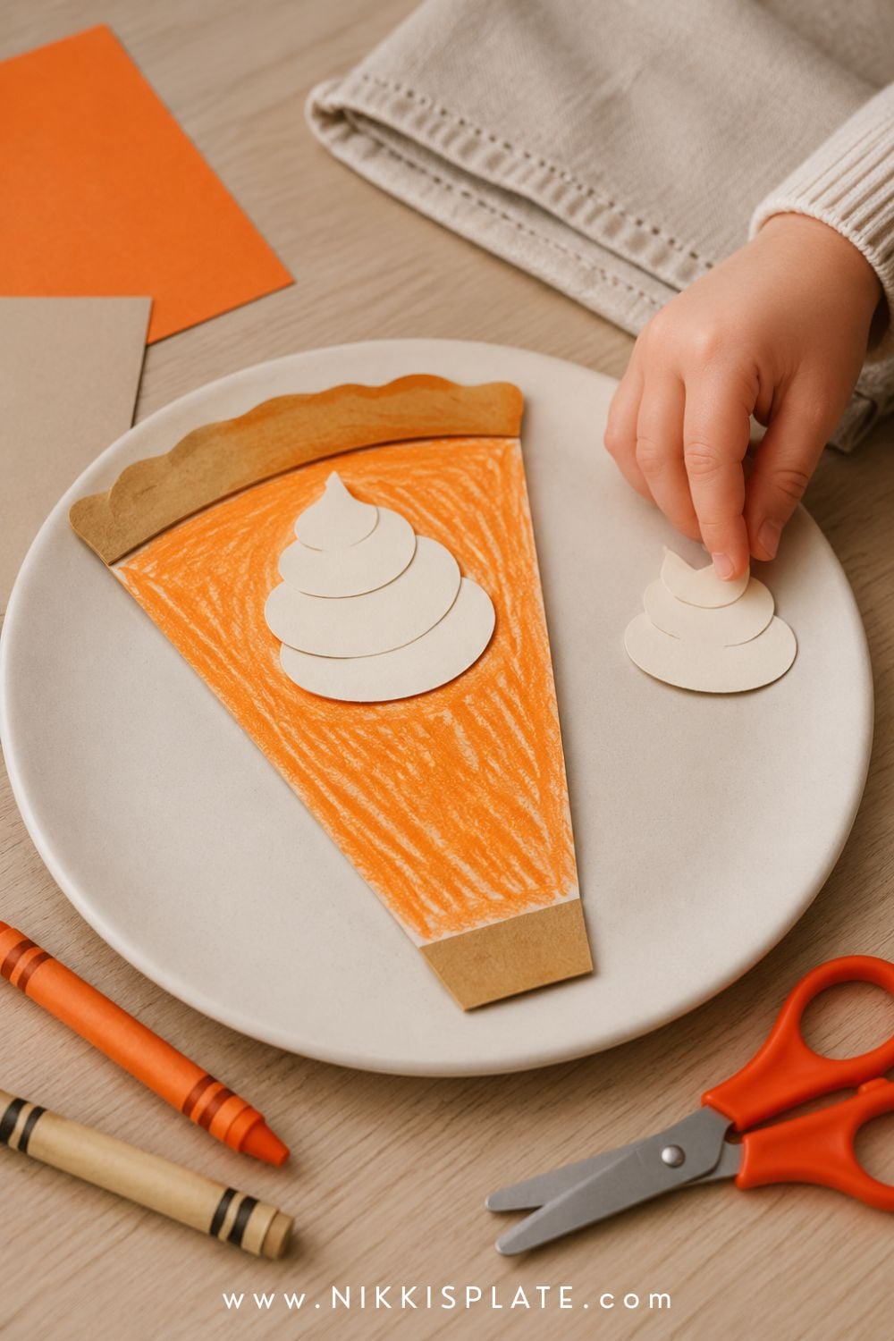 Child-made printable pumpkin pie craft with orange crayon filling, paper crust and a cream whipped topping.
