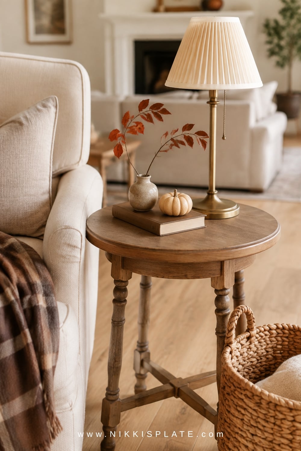 Petite wood side table styled with a bud vase, vintage book and small neutral pumpkin beside a linen chair.