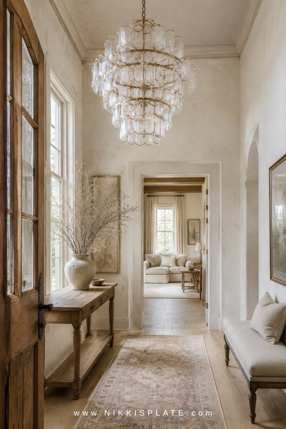 Neutral farmhouse entryway featuring a tiered glass statement chandelier, vintage wood console and soft runner