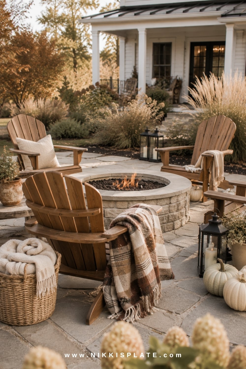 Farmhouse fire pit seating area decorated with plaid blankets, pale pumpkins and black lanterns.