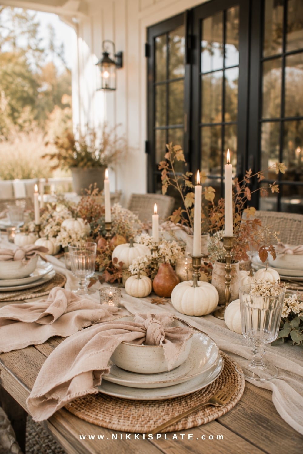 Outdoor farmhouse table styled with cream stoneware, blush napkins, mini pumpkins and autumn branches.