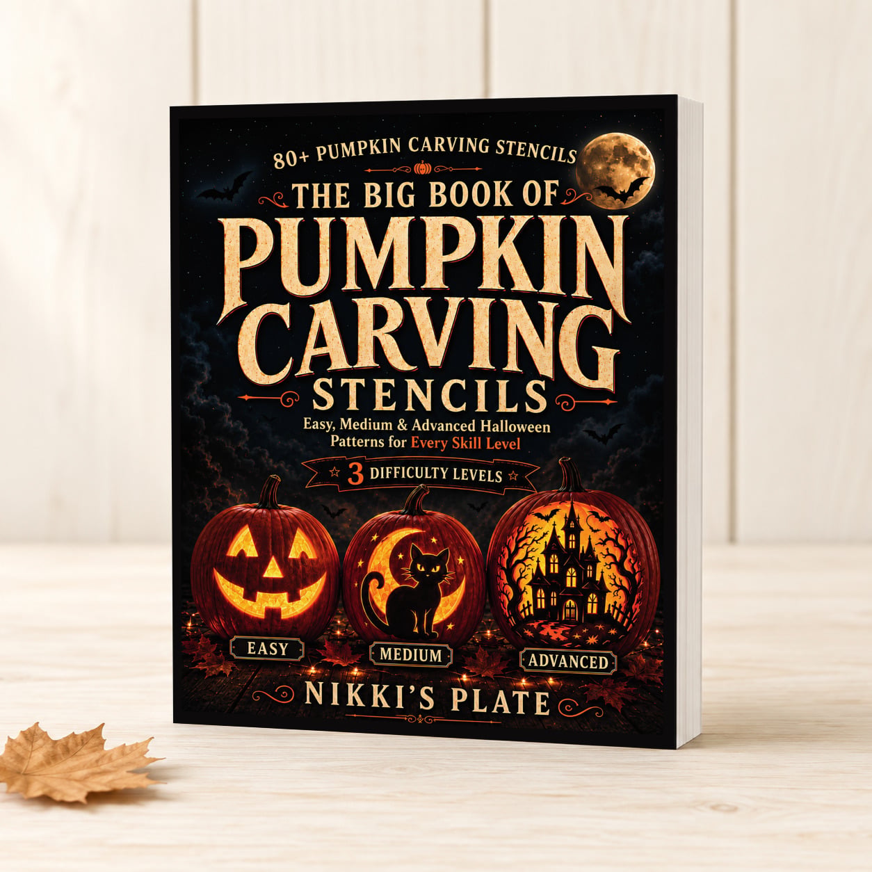 The Big Book of Pumpkin Carving Stencils by Nikki Bahan displayed as a paperback book on a light farmhouse table.