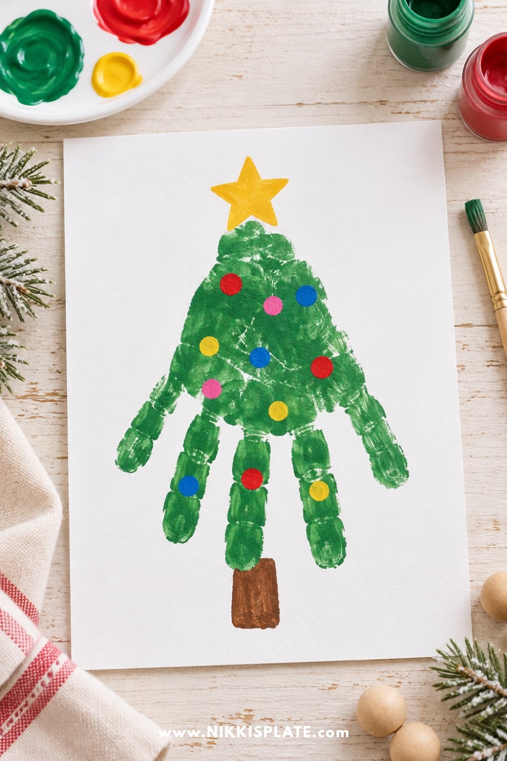 Easy handprint Christmas tree craft for kids with green paint, colorful fingerprint ornaments, a yellow star, and a brown trunk.